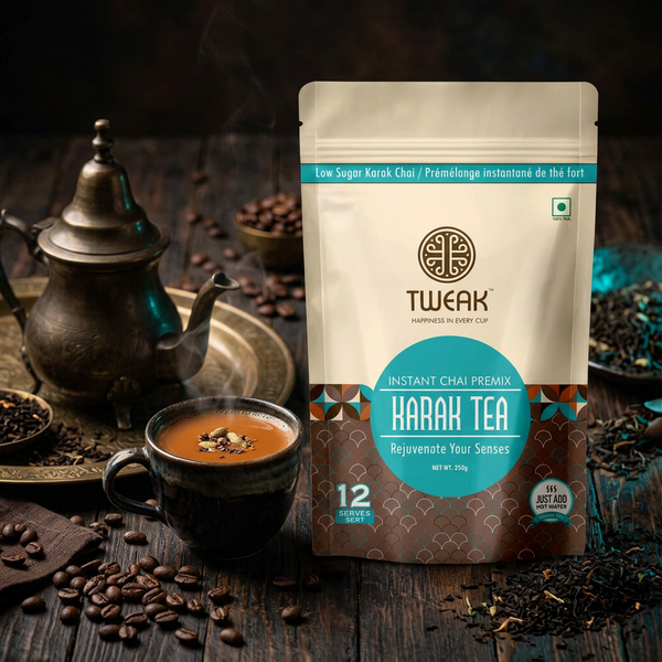A stand-up pouch of Tweak Harah Tea Instant Chai Premix stands on a rustic wooden table beside a dark cup of tea, scattered coffee beans, and a traditional metal teapot.