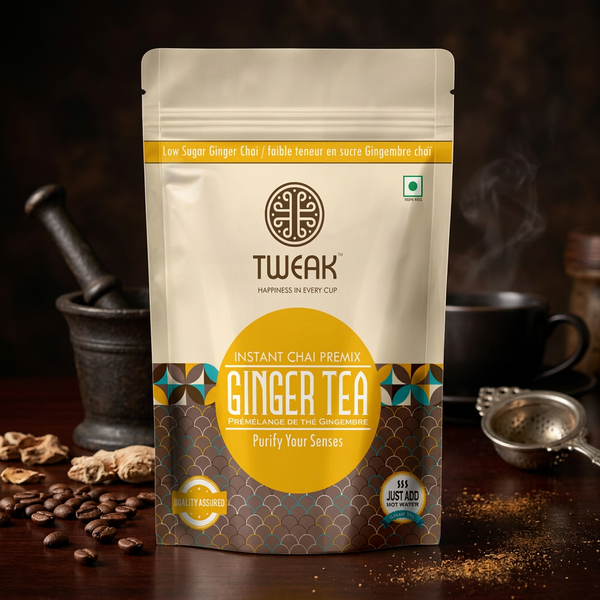 A stand-up pouch of TWEAK Instant Chai Premix Ginger Tea, set on a dark wooden table with coffee beans, a mortar and pestle, and a teapot in the background.